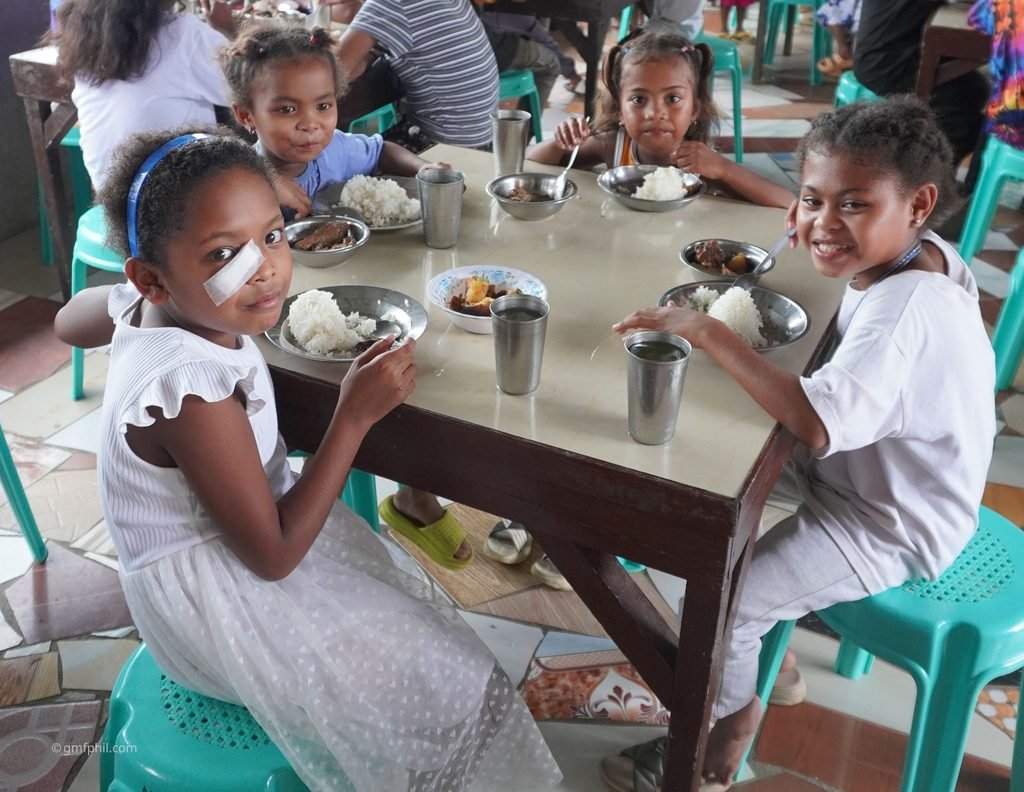 4 Aeta girls at table eating lunch.