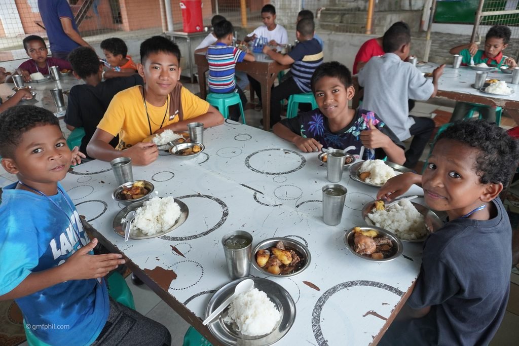 Boys at table eating.