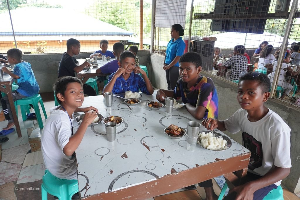 Boys at table enjoying meal.